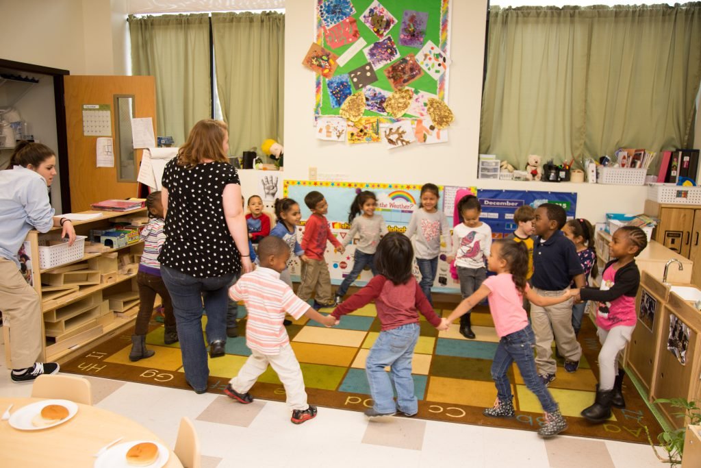 Children and teachers playing Ring Around the Rosie
